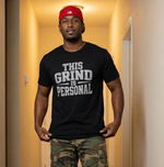 Man wearing a black t-shirt with text  THIS_GRIND_IS_PERSONAL and camouflage pants in a hallway