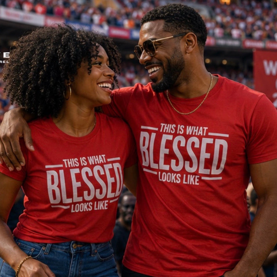 A smiling couple standing together in a crowded stadium, both wearing matching red T-shirts with the slogan 'THIS IS WHAT BLESSED LOOKS LIKE' in large white text. A red 't.