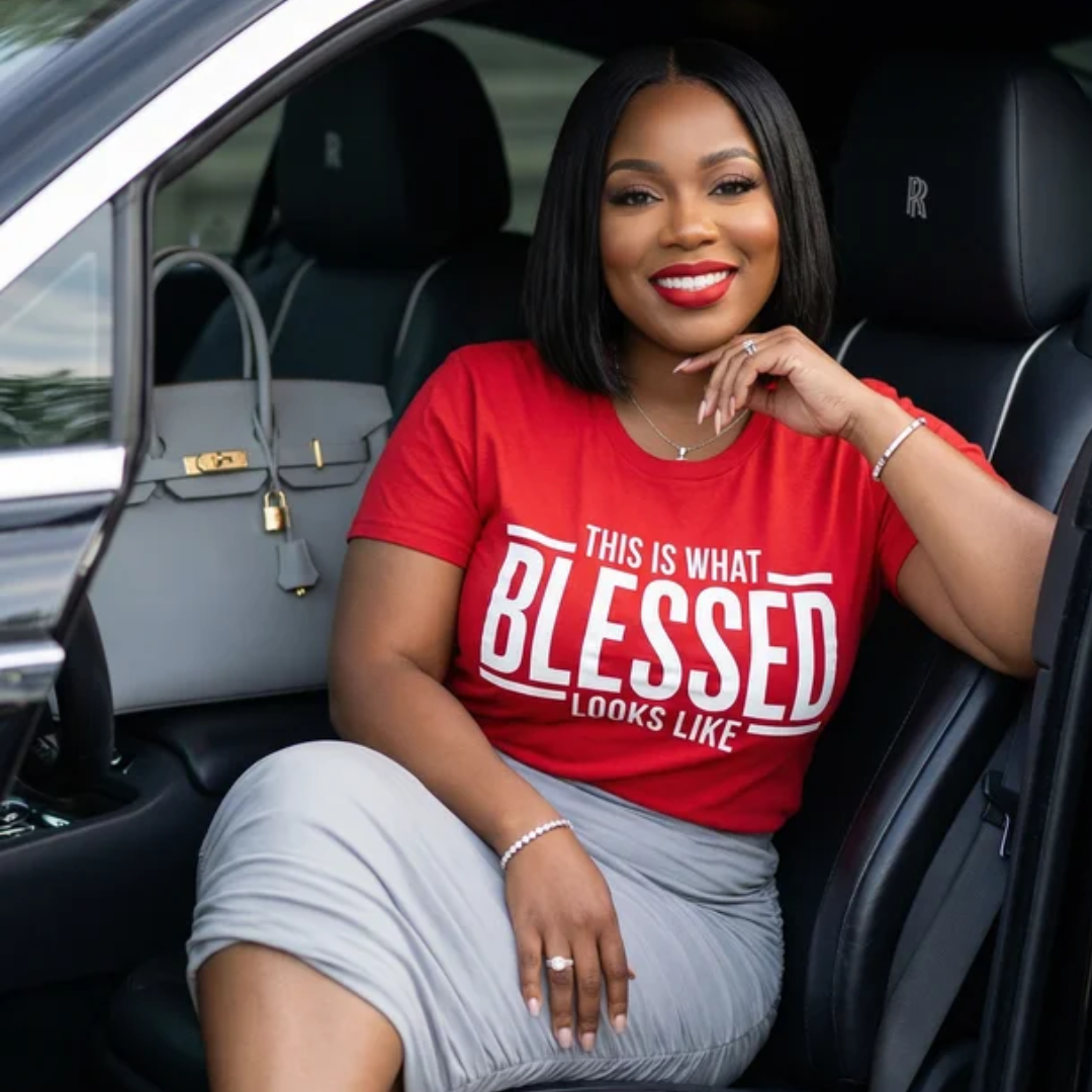 Woman sitting in a car wearing a red 'BLESSED' t-shirt