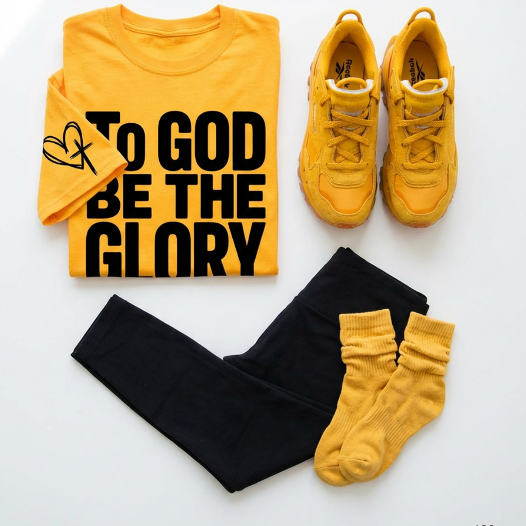 Yellow t-shirt with 'To God Be The Glory' text, yellow sneakers, black pants, and yellow socks on a white background.