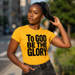 Woman wearing a yellow t-shirt with 'To God Be The Glory' text outdoors.