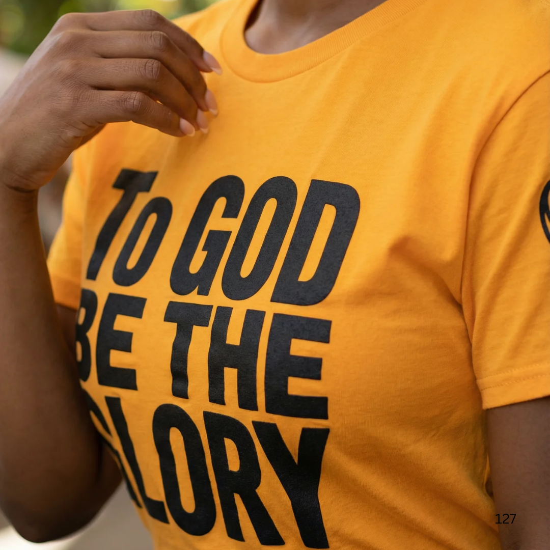 Person wearing a yellow t-shirt with 'To God Be The Glory' text.