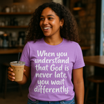 Woman wearing a purple t-shirt with a motivational quote, holding a drink in a casual setting.