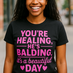 Person wearing a black t-shirt with pink text in an urban setting