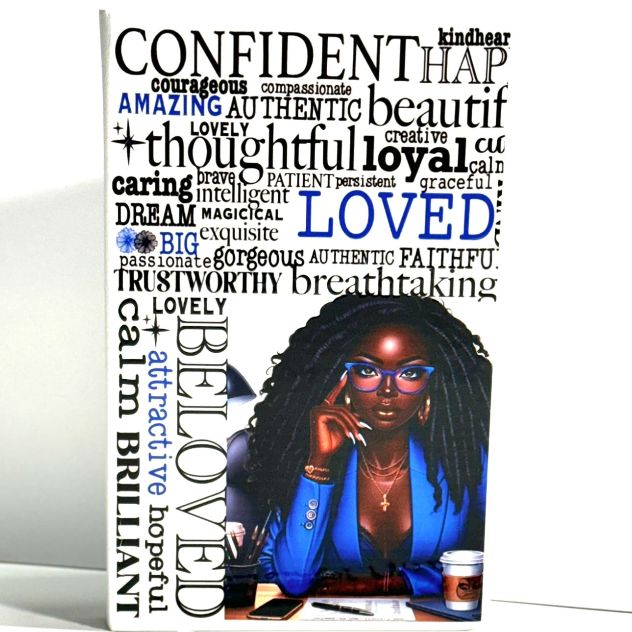 A Confident Love Notebook Journal with a hard cover featuring text and a portrait of a woman. The cover has words like 'amazing', 'authentic', 'beautiful', 'lovely', 'intelligent', 'gracious', 'faithful', 'thoughtful', 'loyal', 'blessed', 'brave', 'inspiring', 'beloved'.