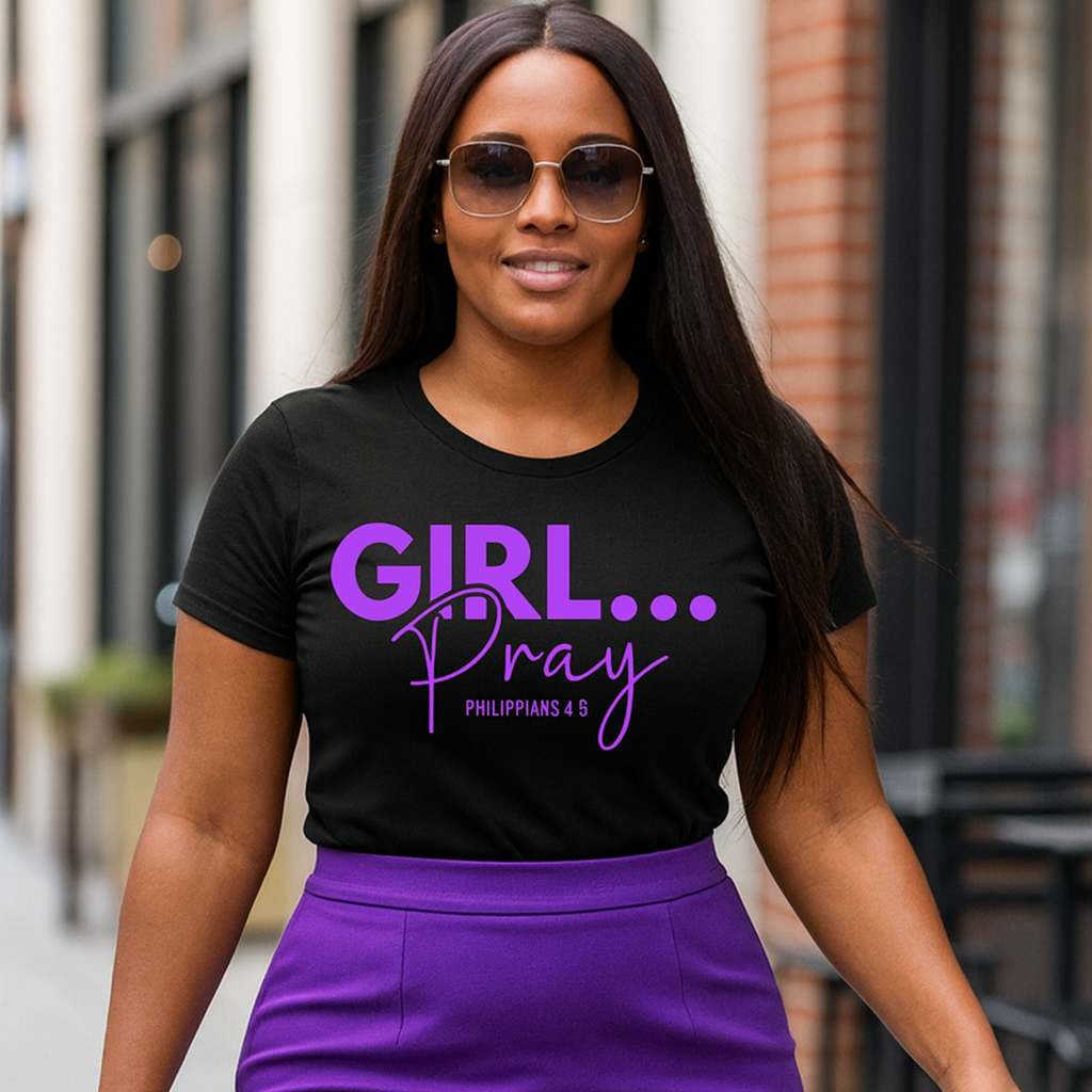 Woman wearing a black t-shirt with 'GIRL... Pray' text and a purple skirt, standing outdoors.