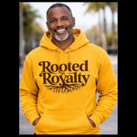 Man wearing a yellow hoodie with 'Rooted in Royalty' text and tree design outdoors.