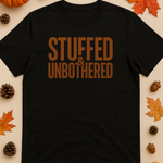 Black t-shirt with 'STUFFED & UNBOtherED' text, surrounded by autumn leaves and pumpkins.